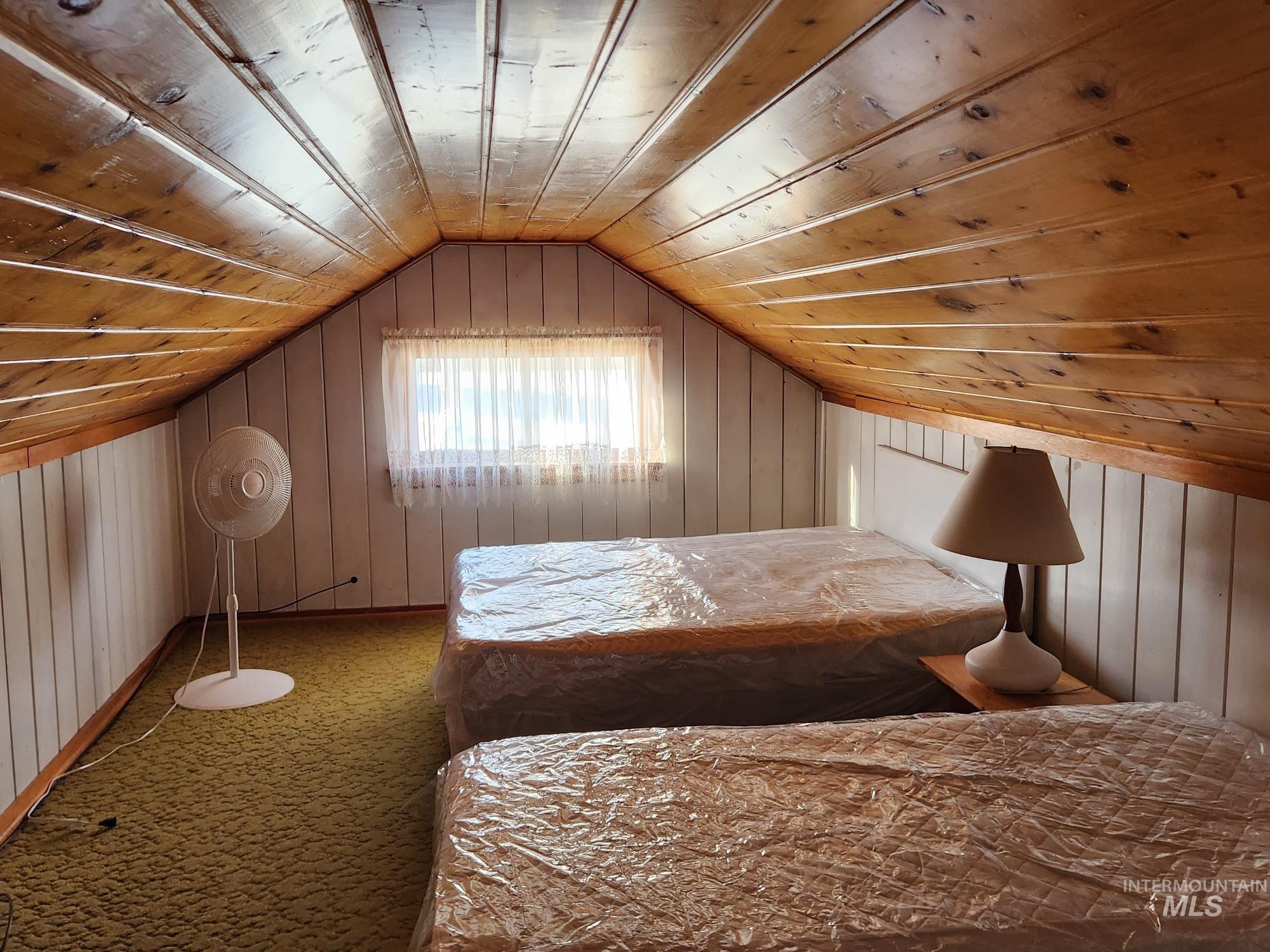 909 12th Street Kamiah, ID 83536 - Photo 22 of 36 Carpeted bedroom featuring wood walls, vaulted ceiling, and wooden ceiling