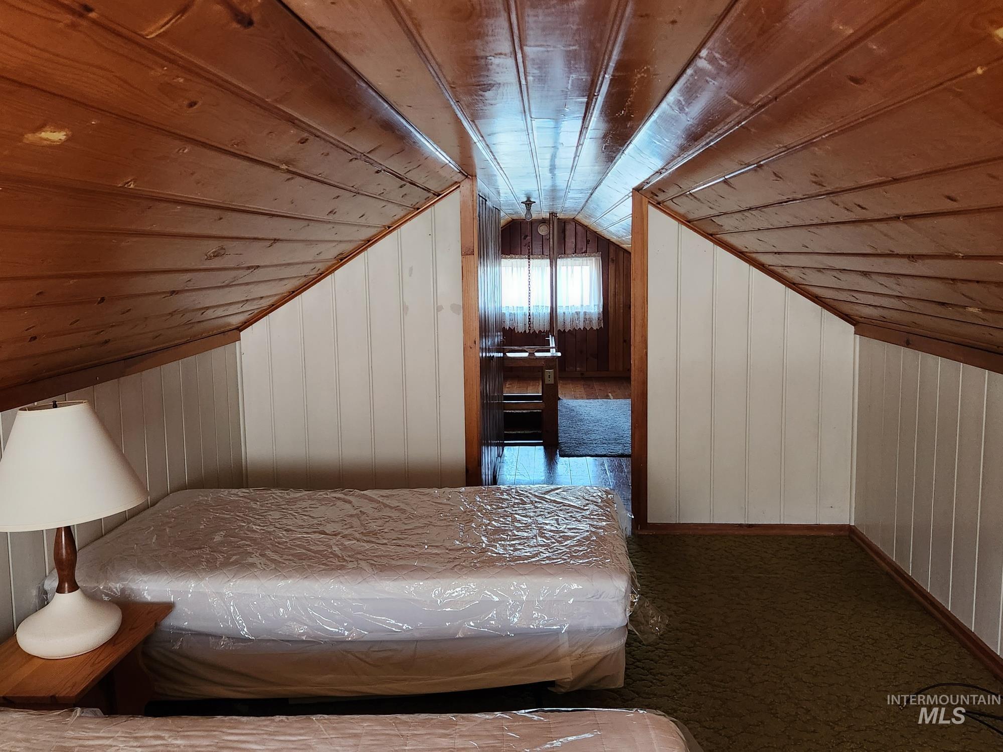 909 12th Street Kamiah, ID 83536 - Photo 23 of 36 Bedroom featuring wood walls, lofted ceiling, wood ceiling, and carpet