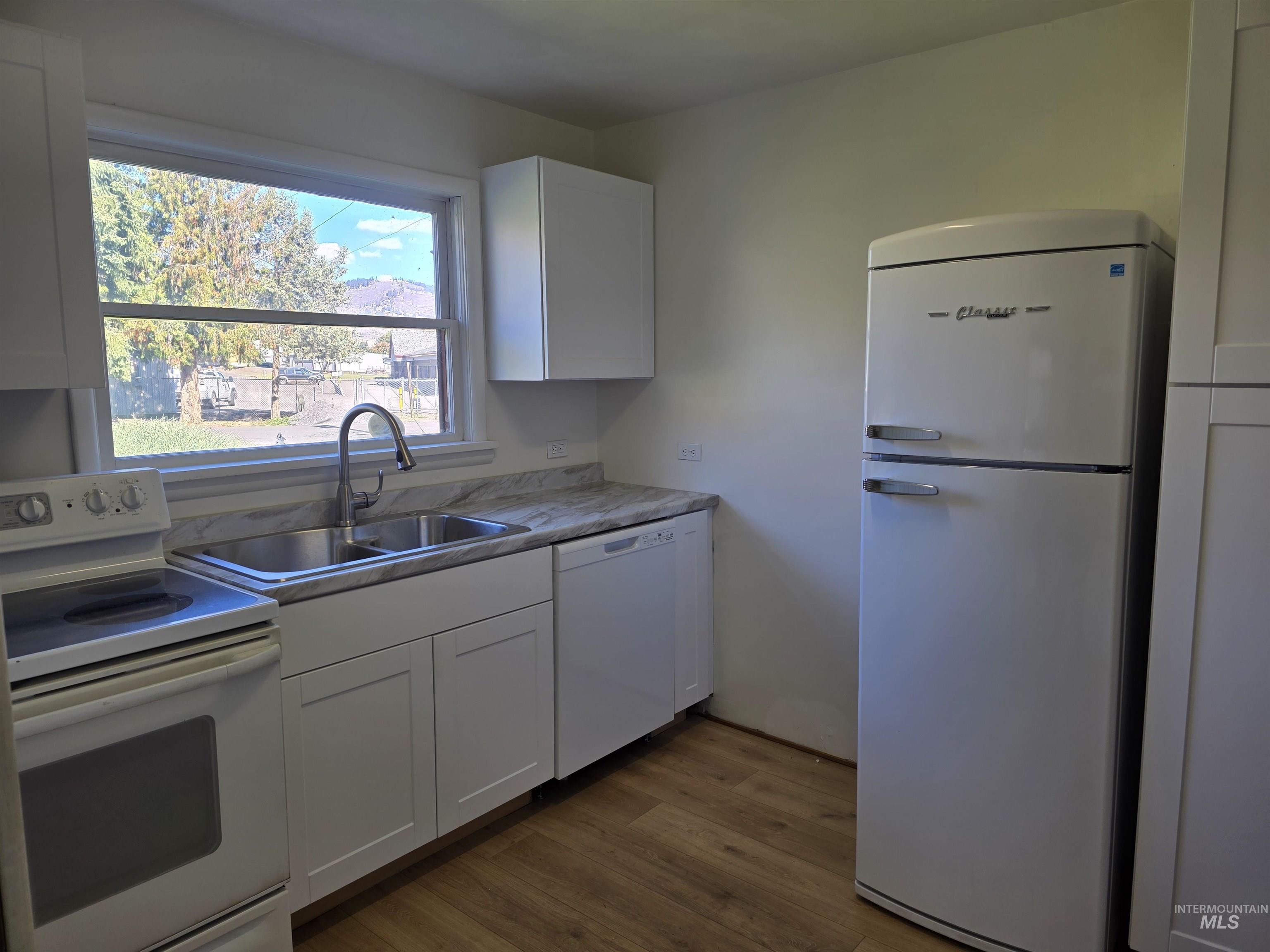 909 12th Street Kamiah, ID 83536 - Photo 10 of 36 Kitchen with white appliances, white cabinets, light wood-style floors, and light countertops