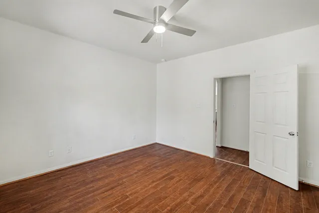 an empty room with wooden floor and ceiling fan
