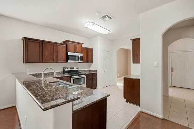 a kitchen with granite countertop a refrigerator and a stove top oven