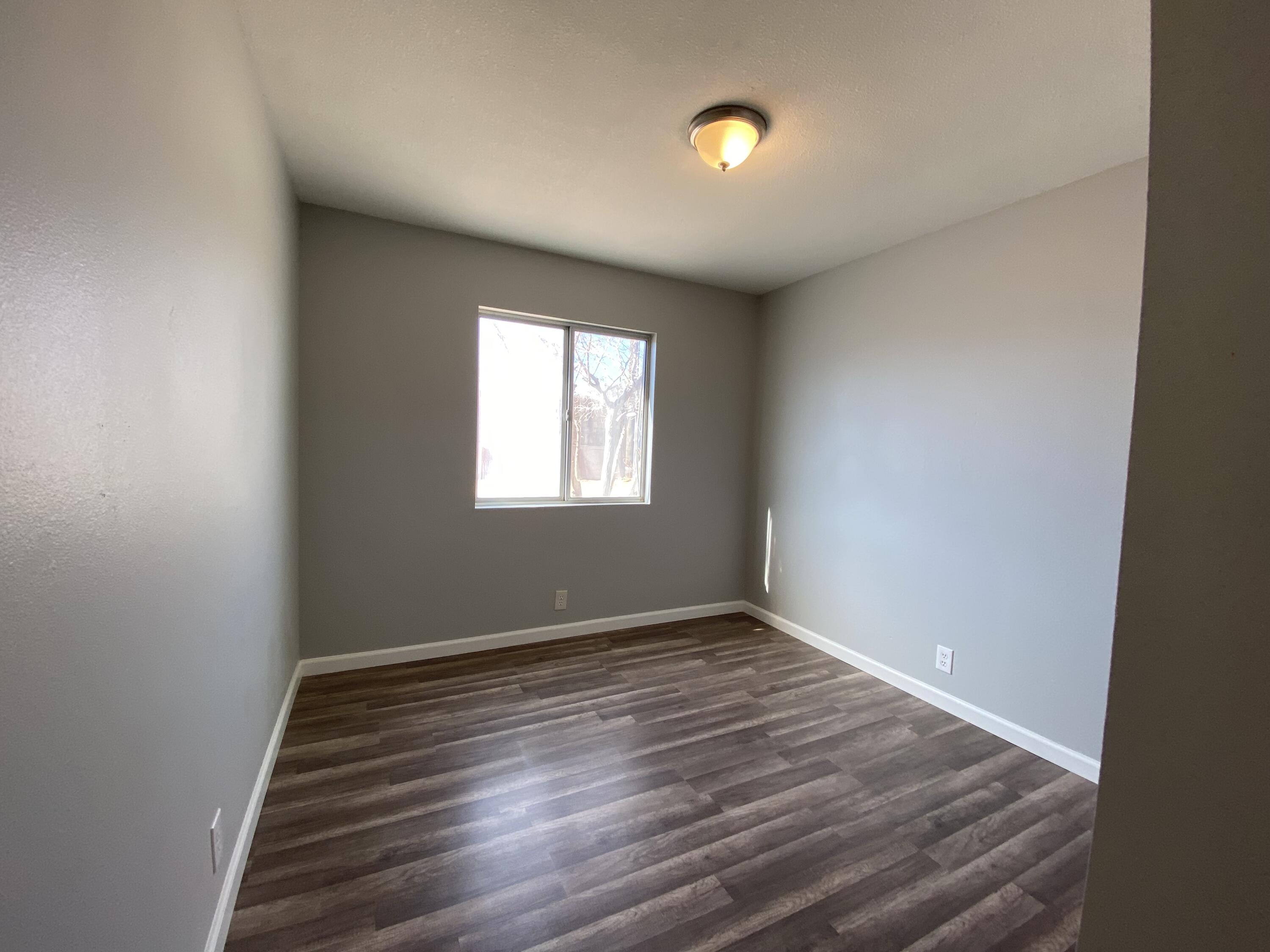 1241 South Ranger Street Ridgecrest, CA 93555 - Photo 11 of 26 an empty room with wooden floor and windows