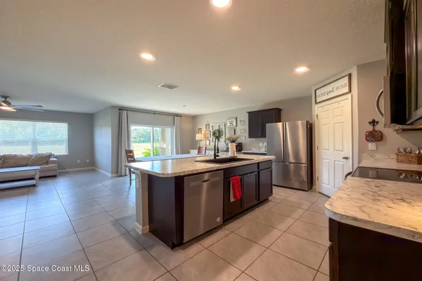 a room with stainless steel appliances kitchen island granite countertop a sink and cabinets