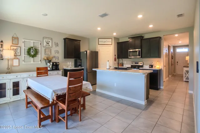 a living room with furniture a flat screen tv and a refrigerator