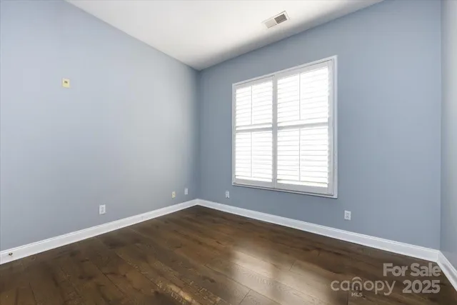 a view of an empty room with wooden floor and closet