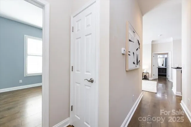 a view of a hallway with wooden floor and a bathroom
