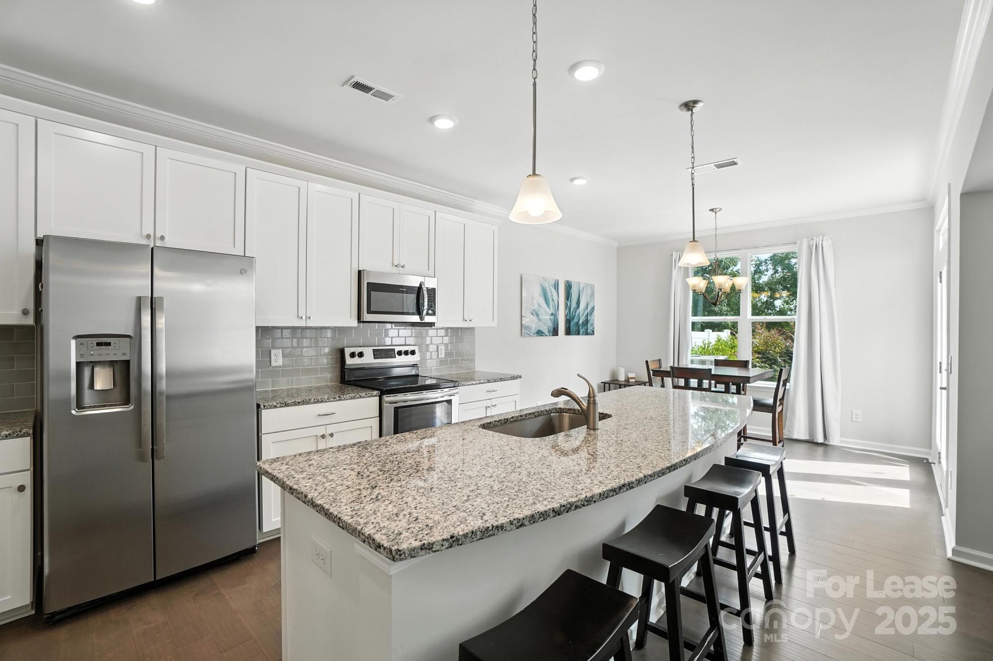 805 River Park Road Belmont, NC 28012 - Photo 8 of 42 a kitchen with stainless steel appliances granite countertop a kitchen island a stove a refrigerator a sink a dining table and chairs with wooden floor
