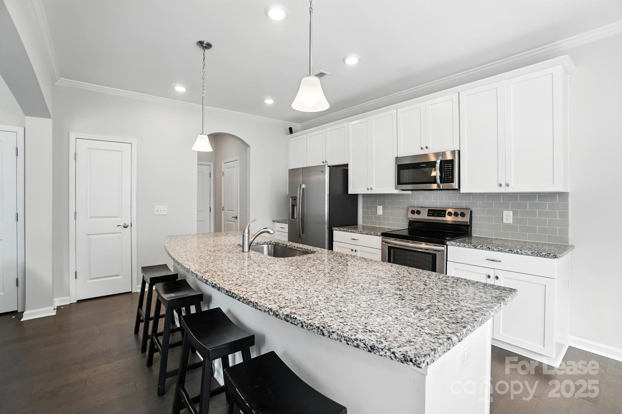 805 River Park Road Belmont, NC 28012 - Photo 10 of 42 a kitchen with kitchen island granite countertop a table chairs microwave and refrigerator