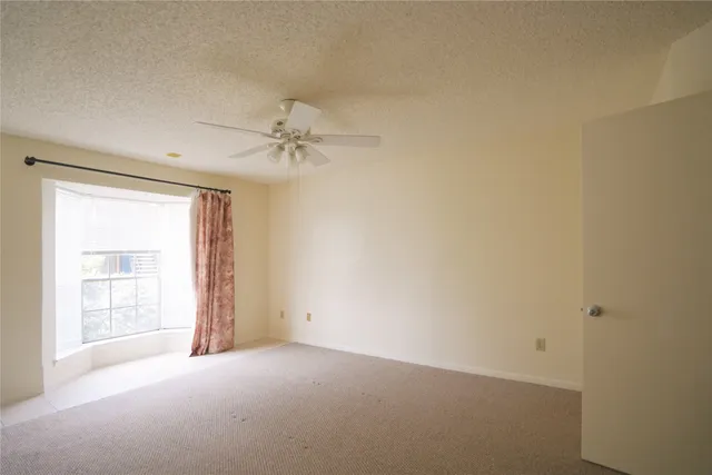 an empty room with a ceiling fan and a window