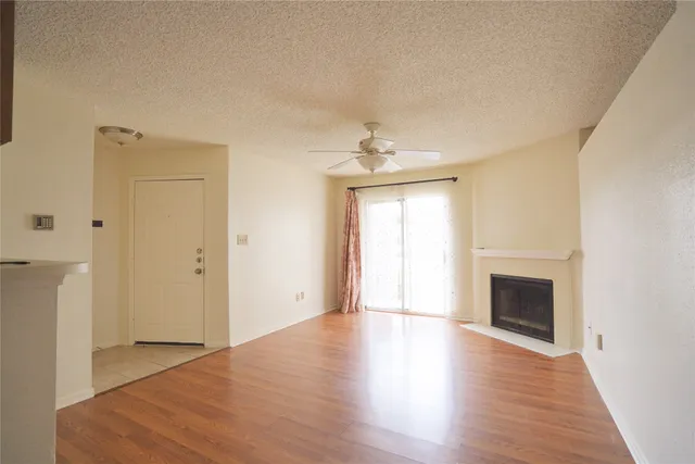 an empty room with wooden floor fireplace and windows