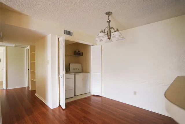 a view of a hallway with wooden floor and a chandelier