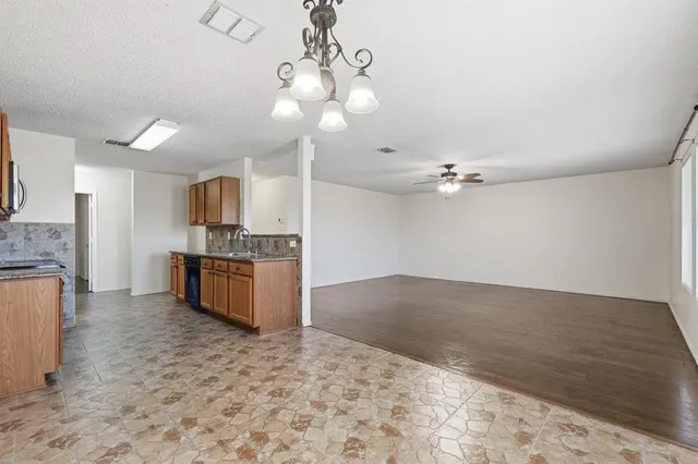 a kitchen with granite countertop stainless steel appliances a sink dishwasher a stove top oven a refrigerator with wooden cabinets and floor