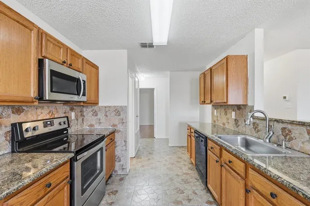a kitchen with stainless steel appliances granite countertop a sink stove and refrigerator