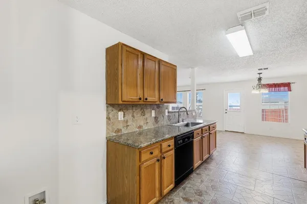 an empty room with chandelier fan and windows