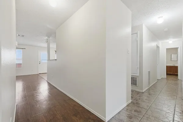 an empty room with wooden floor chandelier fan and windows