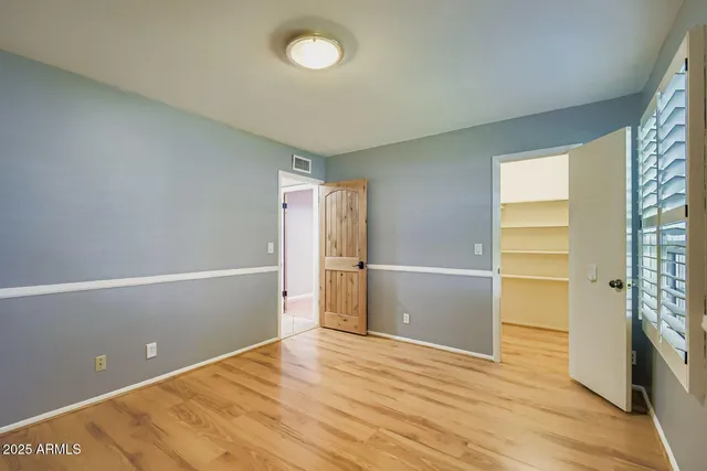 a view of empty room with wooden floor and fan