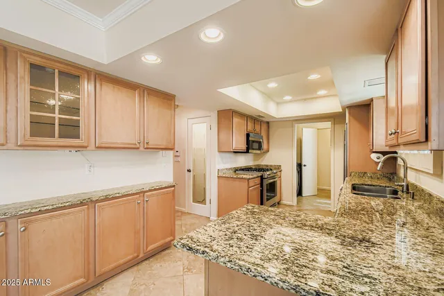 a kitchen with stainless steel appliances granite countertop a stove top oven a sink a refrigerator and white cabinets