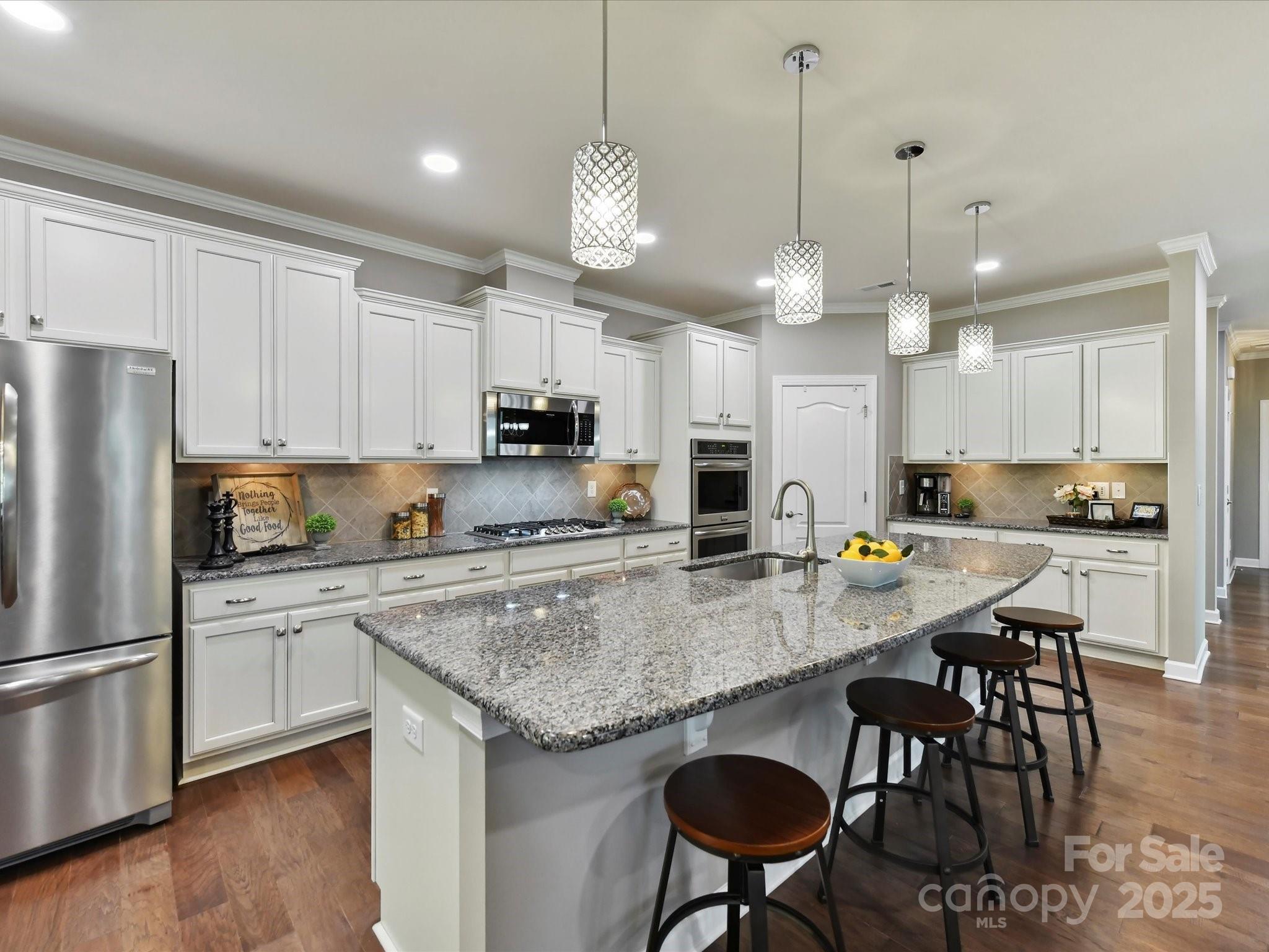 2972 Arches Bluff Circle Lancaster, SC 29720 - Photo 14 of 47 a kitchen with stainless steel appliances granite countertop a stove a refrigerator a kitchen island a sink and white cabinets with wooden floor