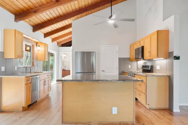 a large kitchen with stainless steel appliances granite countertop a stove a sink dishwasher and a refrigerator with wooden floor