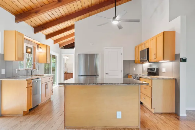 a large kitchen with stainless steel appliances granite countertop a stove a sink dishwasher and a refrigerator with wooden floor