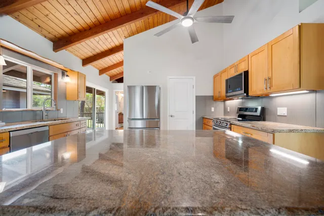 a view of a kitchen with stainless steel appliances granite countertop a stove top oven a sink a dining table and chairs with the view of kitchen