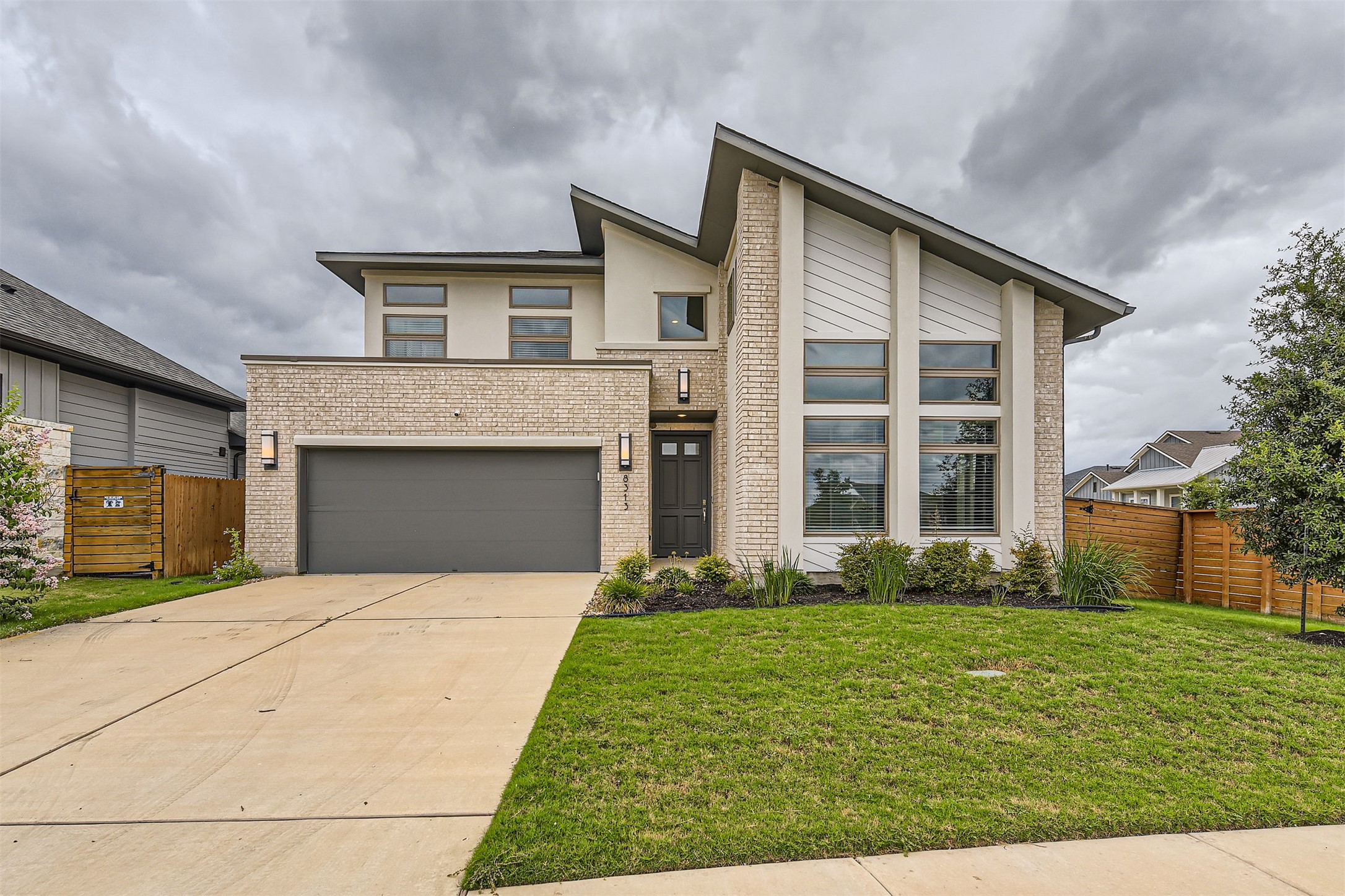 Modern architecture defines this dwelling, with a wide driveway leading to the integrated garage and a landscaped front yard.
