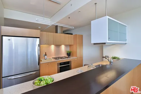 a view of kitchen with stainless steel appliances granite countertop a stove top oven a sink and a refrigerator