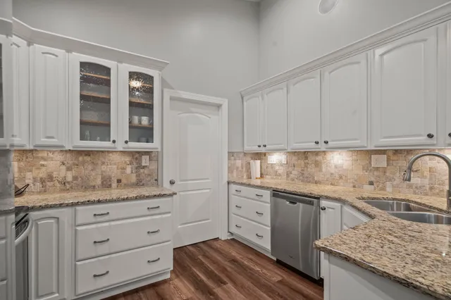 a kitchen with granite countertop white cabinets and stainless steel appliances