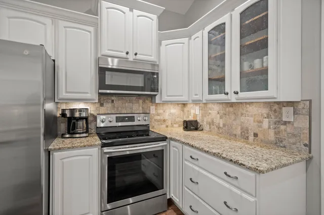 a kitchen with granite countertop white cabinets stainless steel appliances and a counter space