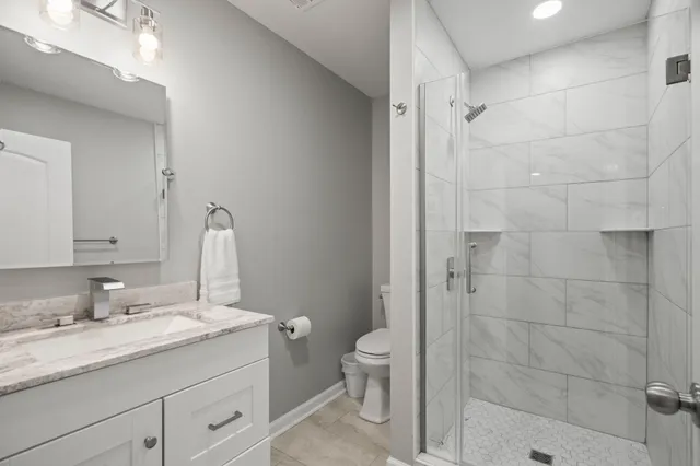 a bathroom with a granite countertop sink a toilet and shower