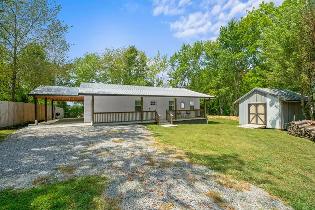 a front view of a house with a garden and trees