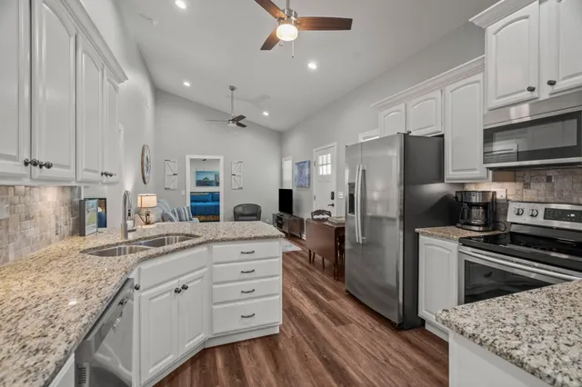 a kitchen with kitchen island granite countertop a sink stainless steel appliances and cabinets