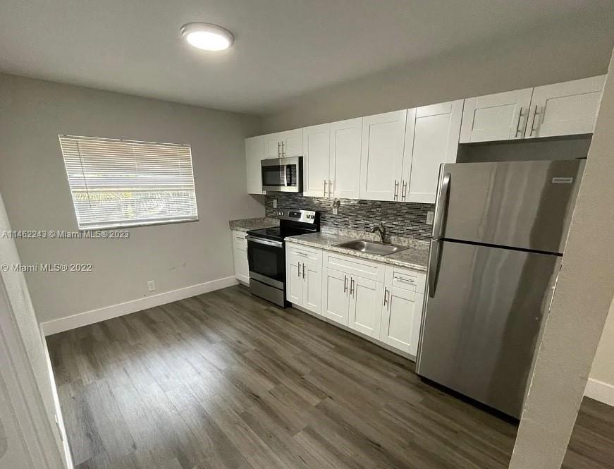 450 Southwest 2nd Street, Unit 4 Pompano Beach, FL 33060 - Photo 1 of 9 a kitchen with a refrigerator a stove top oven and wooden floor