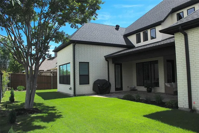 a view of a yard in front of a brick house with a large tree