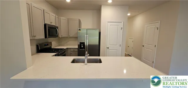 a kitchen with a refrigerator a stove top oven a sink and cabinets
