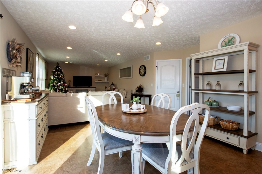 4750 McCauley Road Wooster, OH 44691 - Photo 12 of 37 Dining room featuring a textured ceiling and a notable chandelier