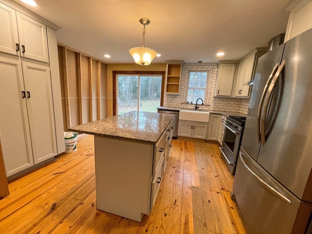 163 East Rindge Road Ashburnham, MA 01430 - Photo 18 of 42 a kitchen with kitchen island granite countertop a refrigerator a sink dishwasher and wooden cabinets with wooden floor
