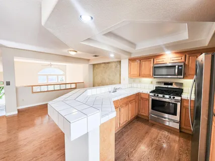 a kitchen with stainless steel appliances kitchen island granite countertop a stove a sink and a refrigerator