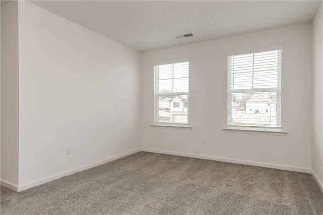 an empty room with windows and refrigerator