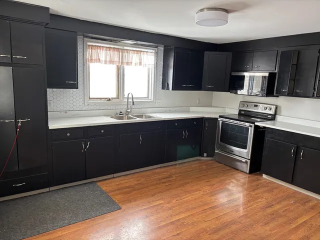 a kitchen with stainless steel appliances granite countertop a sink window and cabinets