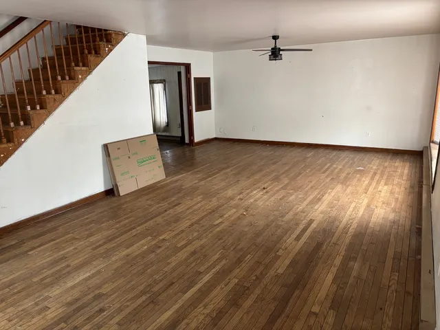 a view of a livingroom with wooden floor and a ceiling fan