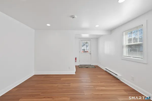 a view of an empty room with wooden floor and a window