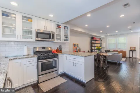 a kitchen with granite countertop stainless steel appliances a sink window and cabinets