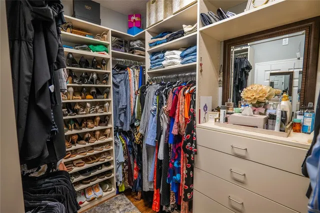a view of walk in closet with clothes and shoes