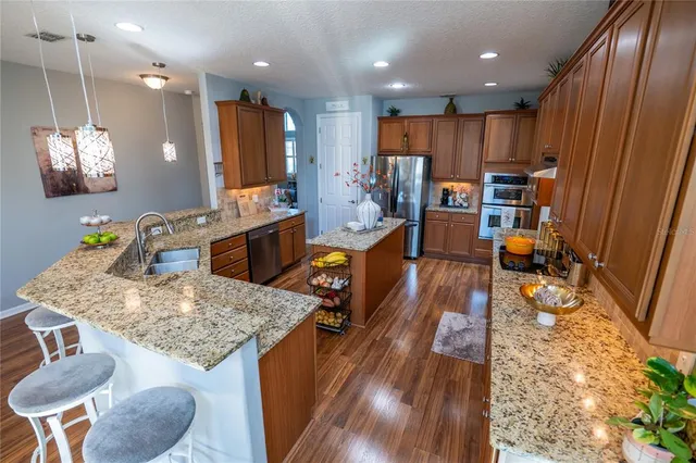 a view of a kitchen with kitchen island granite countertop wooden floor and a refrigerator