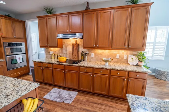 a kitchen with stainless steel appliances granite countertop wooden cabinets a refrigerator and sink