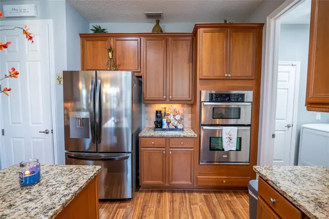 a kitchen with granite countertop a refrigerator and a stove top oven