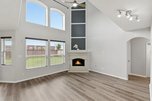 a view of an empty room with wooden floor fireplace and a window