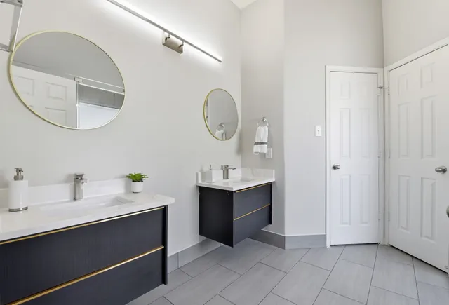 a spacious bathroom with a double vanity sink mirror and bathtub