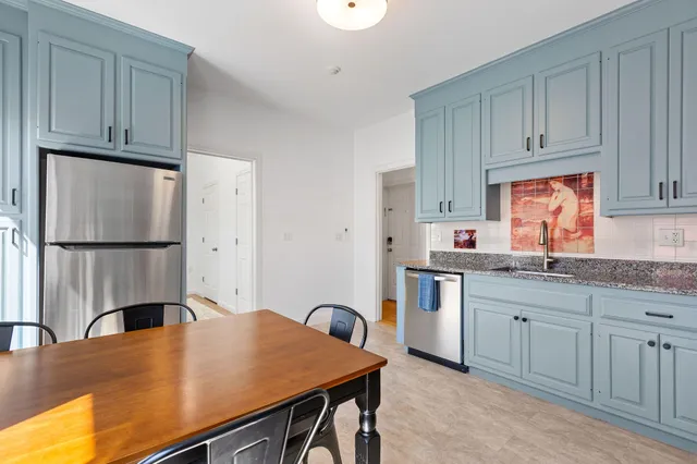 a kitchen with granite countertop stainless steel appliances white cabinets and a sink